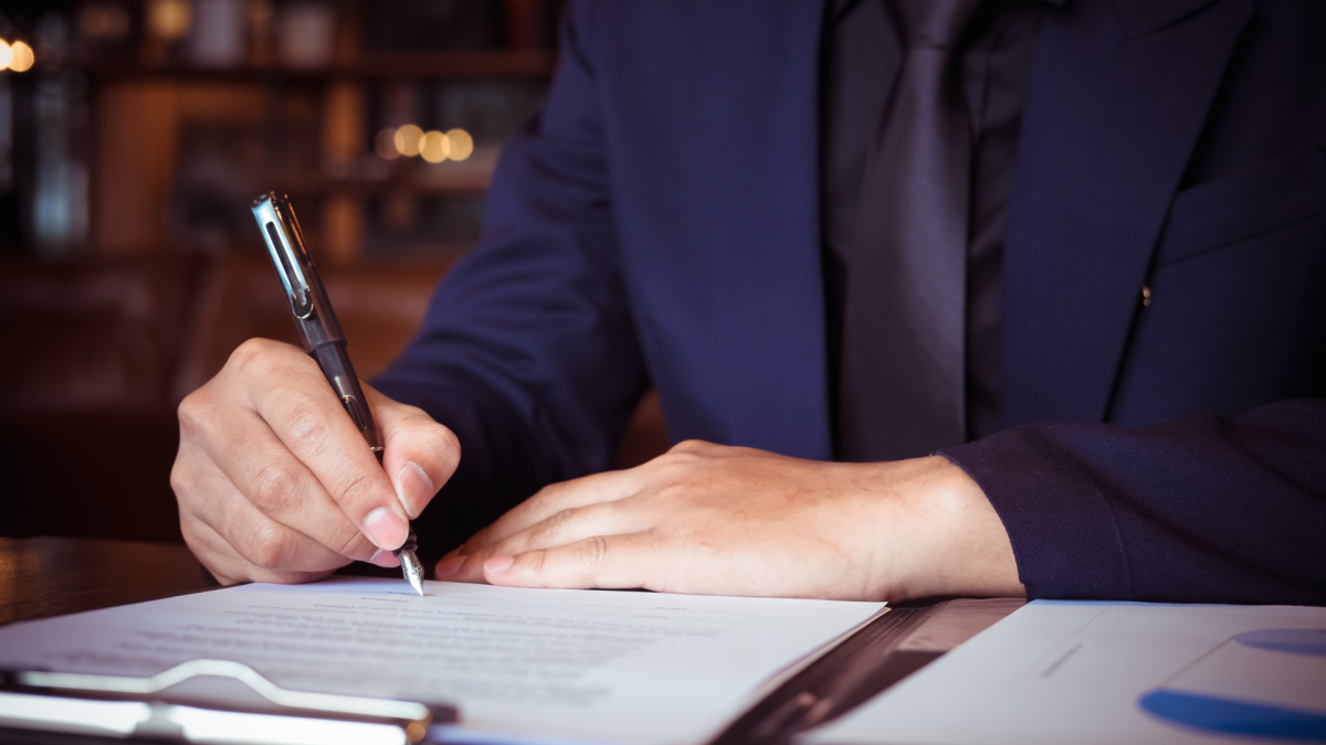 Homme en costume ecrivant sur un document
